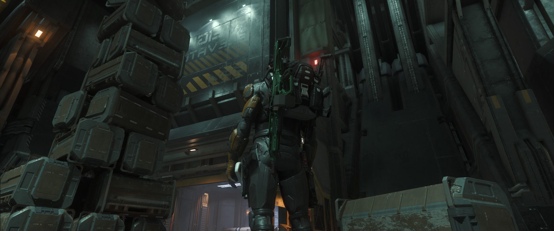 Un joueur en armure, de dos, devant une pile de caisses de fret au pied d'un monte-charge, dans Star Citizen